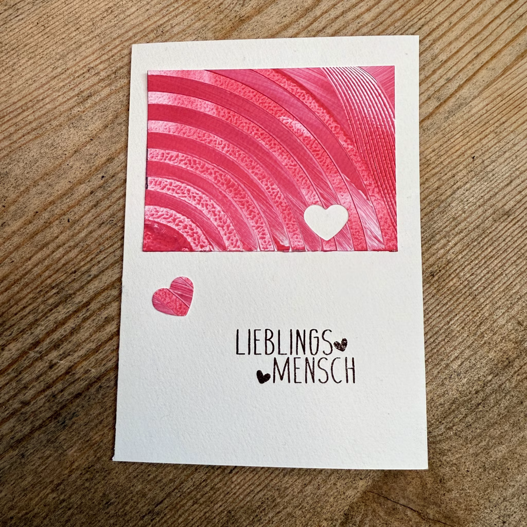 Handgemachte Valentinskarte liegt auf Holz. Die Karte zum Valentinstag ist in den Farben Rot und Weiß mit zwei süßen Herzen und der Aufschrift Lieblingsmensch. Perfekt für Valentinstag und Hochzeitstag.