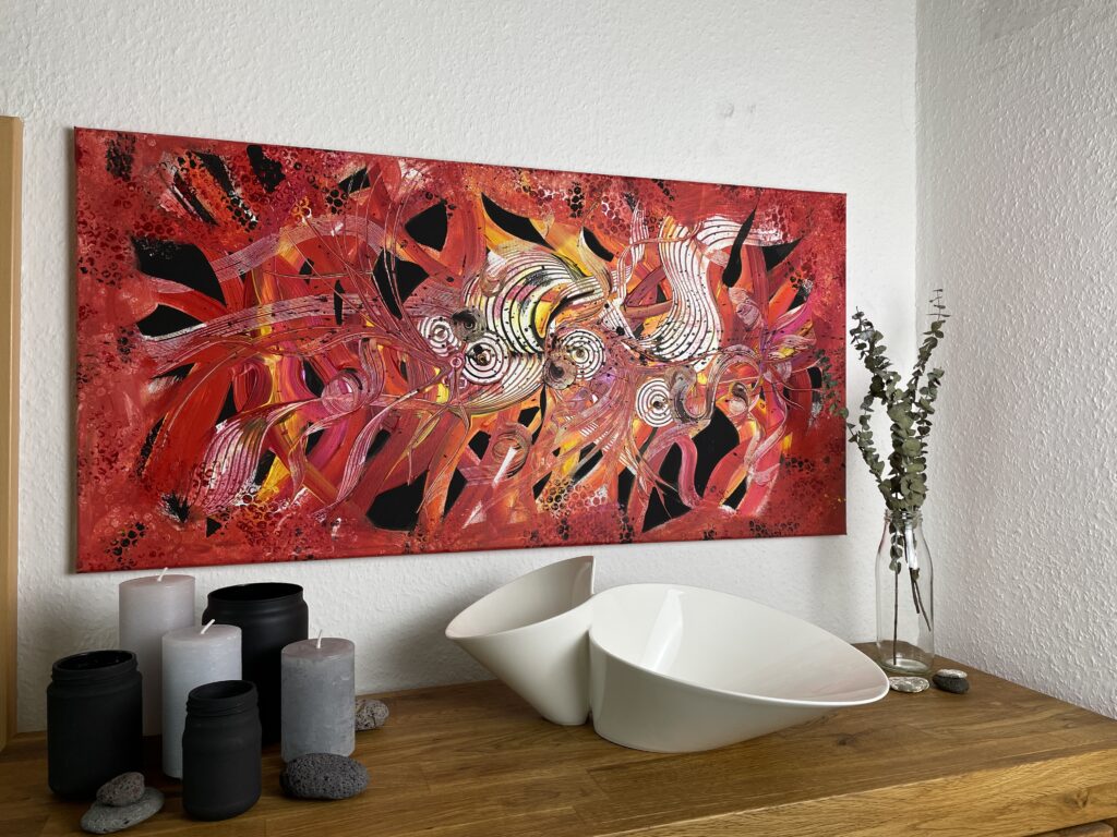 Tipps Kauf von Kunstwerken: Ein rot schwarzes Acrylgemälde im modernen Design, das an einer Wohnzimmerwand über einem Sideboard hängt. Auf dem Möbelstück stehen graue Kerzen, schwarze Gefäße, eine weiße Schale und eine Glasvase mit getrocknetem Eukalyptus. Das moderne Gemälde ist 50 cm x 100 cm groß.