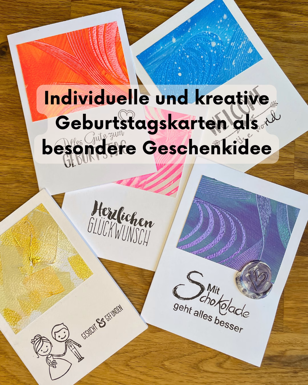 Handgemachte Unikat-Grußkarten von Janiscolorart als kreative Geschenkidee. Fünf individuelle Geburtstagskarten mit farbenfroher, abstrakter Kunst von Janina Feld aus dem Saarland auf einem Holztisch arrangiert.
