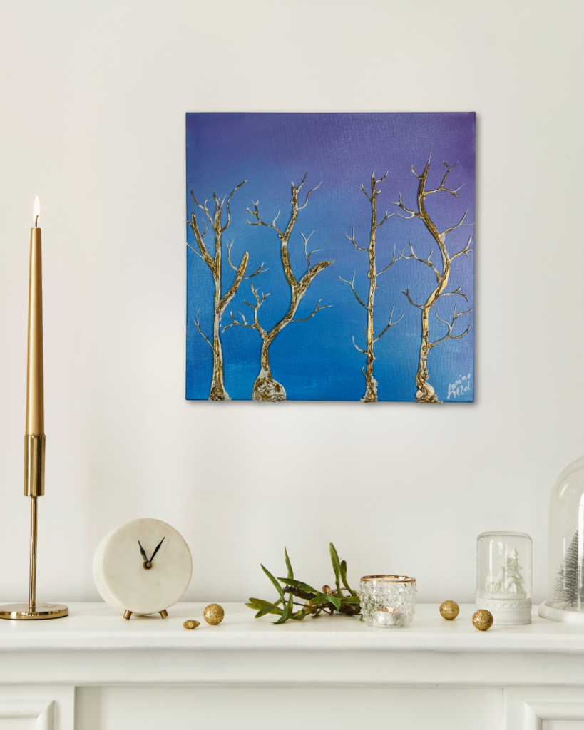 Abstrakte Acrylmalerei, die eine Winterlandschaft mit goldenen Bäumen darstellt. Das edle Gemälde hängt über einem Weißen Sideboard mit goldenen Kerzen.