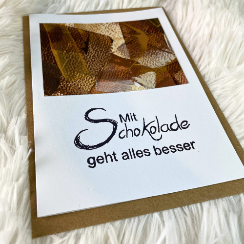 Individuelle Bestellungen für deine handgefertigten Grußkarten von Janiscolorart. Die Grußkarte mit der Aufschrift "Mit Schokolade geht alles besser" ist dunkelbraun, hellbraun, beige und Goldakzenten.