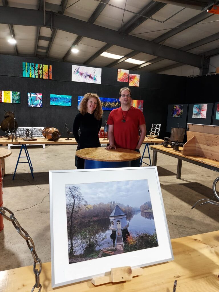 Vernissage in der Kreativwerkstatt Illingen mit der modernen Künstlerin Janina Feld aus Neunkirchen Saar und dem Saarland Fotografen Sven Kley aus Merchweiler. Im Vordergrund ist eine Fotografie von Sven Kley, auf der man den Itzenplitzer Weiher mit Pumpenhaus sieht.