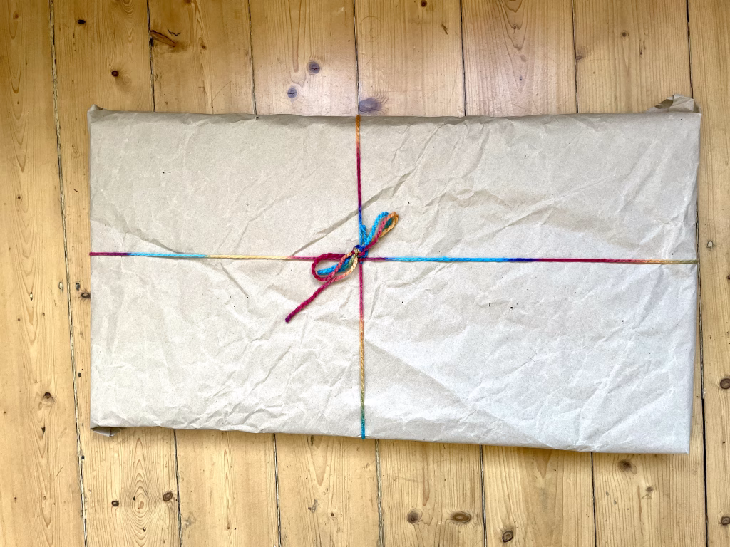 Kunst sicher versenden: Fertig verpacktes Acrylgemälde von der deutschen Künstlerin Janiscolorart. Das Paket steht auf einem Tisch im Künstleratelier.