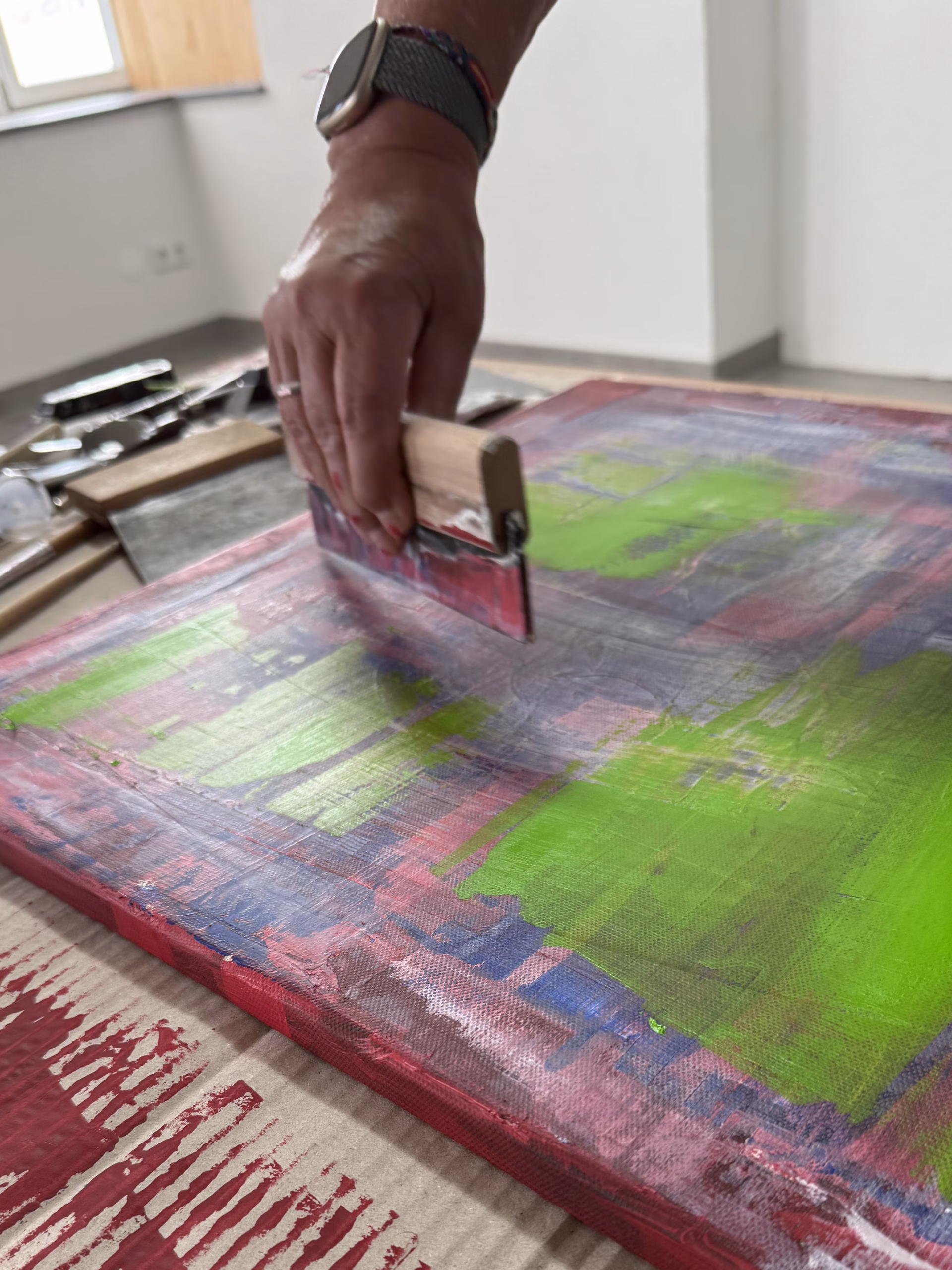 Kunst Events 2026: Malkurs mit der Spachtel. Hand hält Spachtel über der bemalten Leinwand.