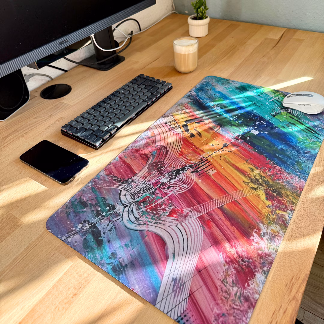Mauspads mit Kunstdruck der Künstlerin Janiscolorart. Das bunte XXL Mauspad liegt auf einem Holzschreibtisch.